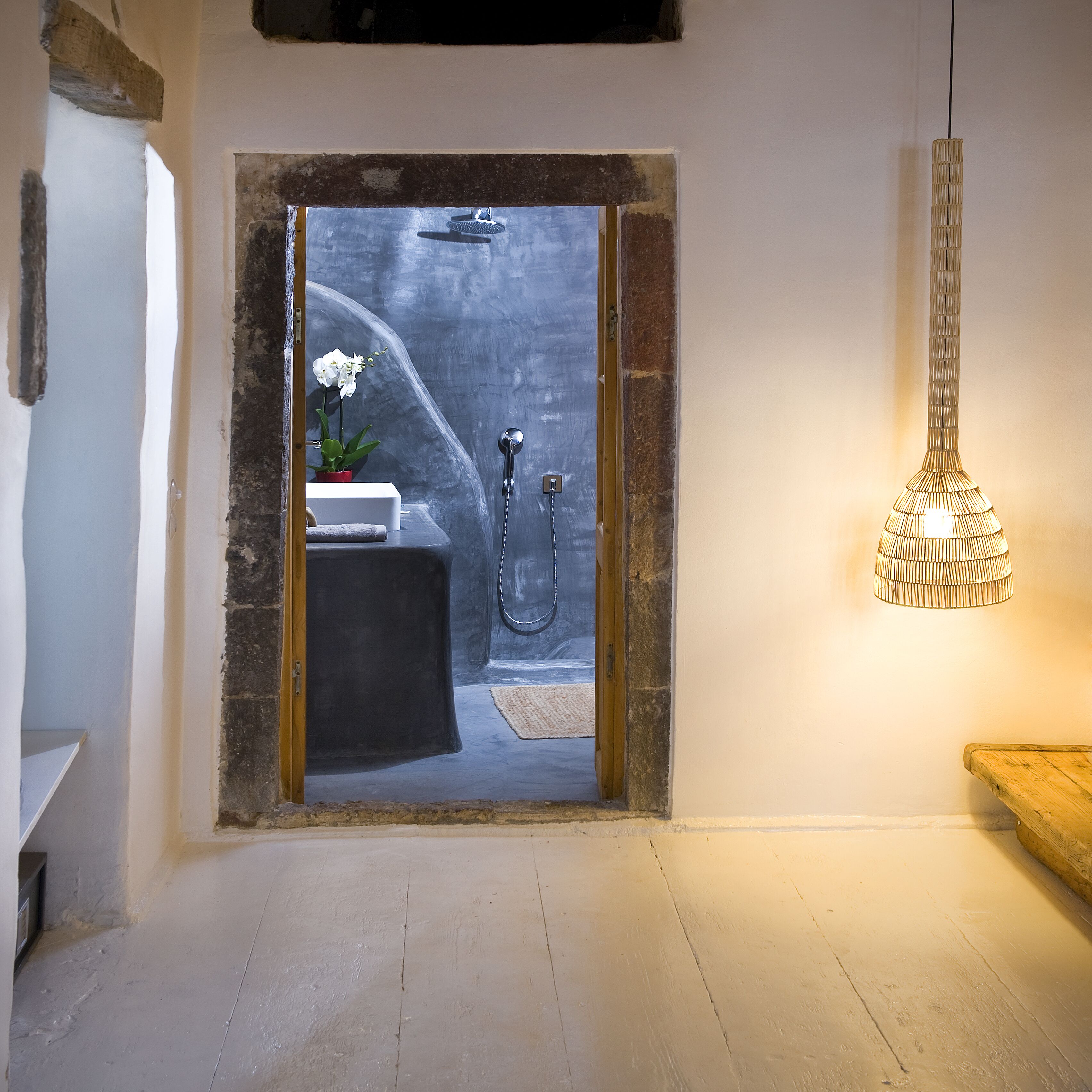 A bathroom with a shower, a sink, and a hanging light fixture.