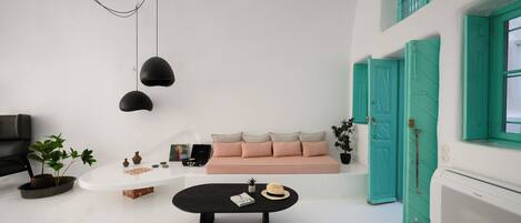 A minimalist living room with a sofa, a coffee table, a TV, and a potted plant.