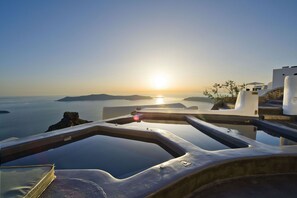 A view from a balcony overlooking a body of water with a sunset in the background. - Sophia Luxury Suites (Santorini)
