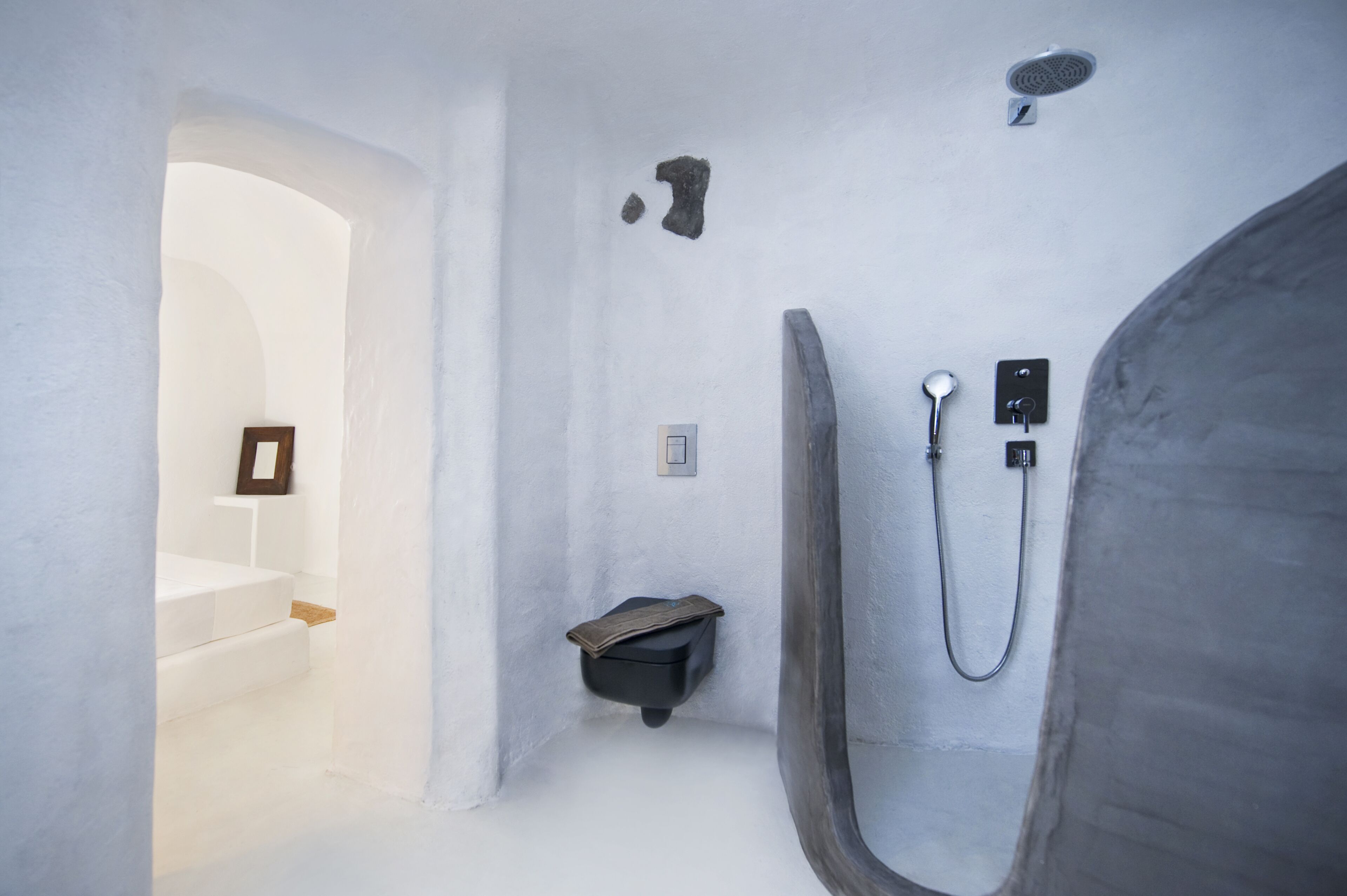 A minimalist bathroom with a shower, a small sink, and a framed picture on the wall.