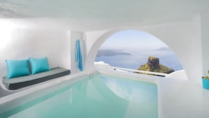 A modern, minimalist room with a large window overlooking a scenic view of the sea and a rocky island.