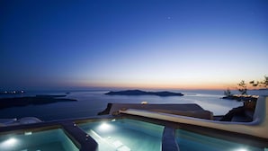 A pool area with clear views of the sea and distant islands at dusk.