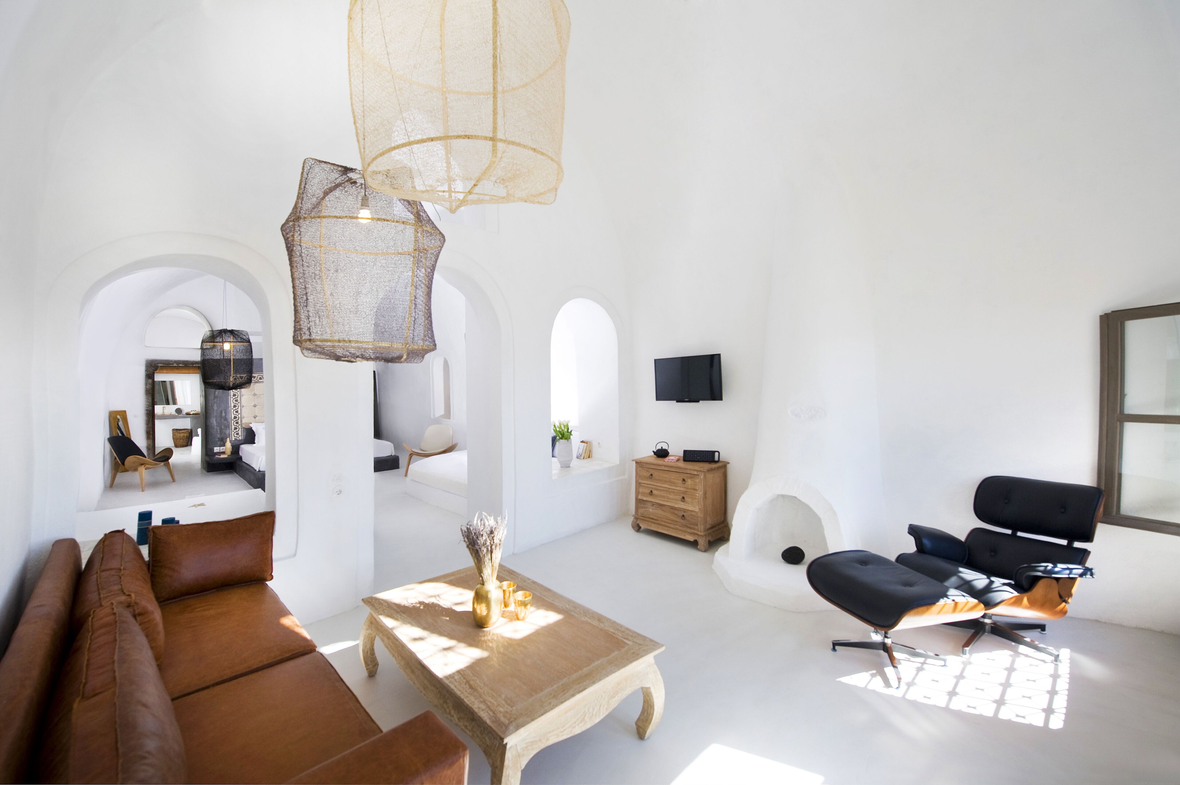 Un salon spacieux avec un canapé en cuir marron, une table basse en bois et un fauteuil de bureau noir.