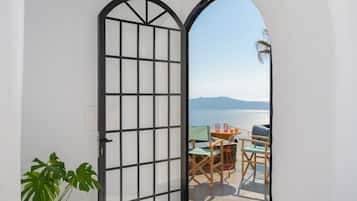 A room with a view of the sea, a table with chairs, and a potted plant.