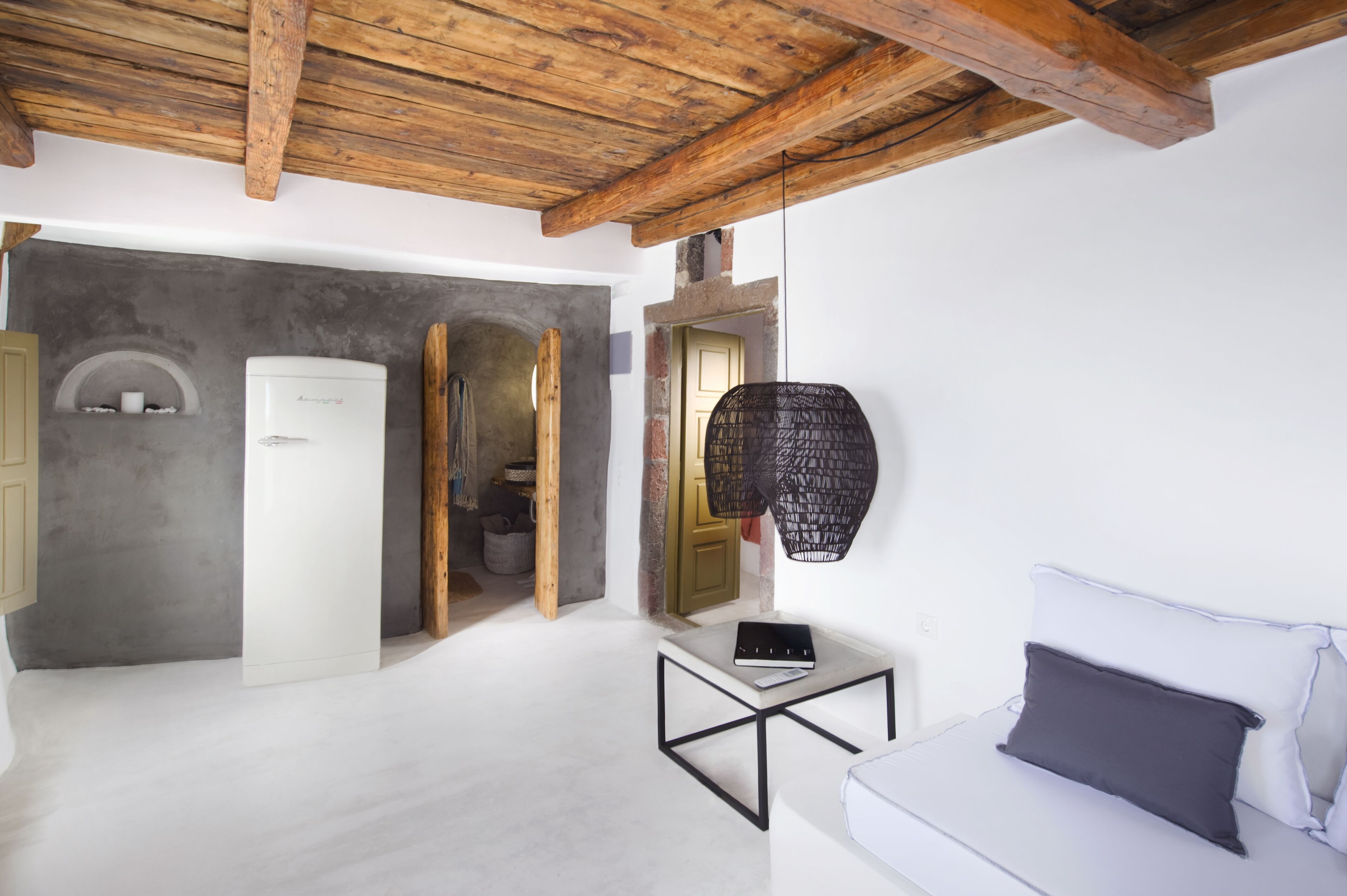 A modern room with a wooden ceiling, a white sofa, a small table, and a hanging light fixture.