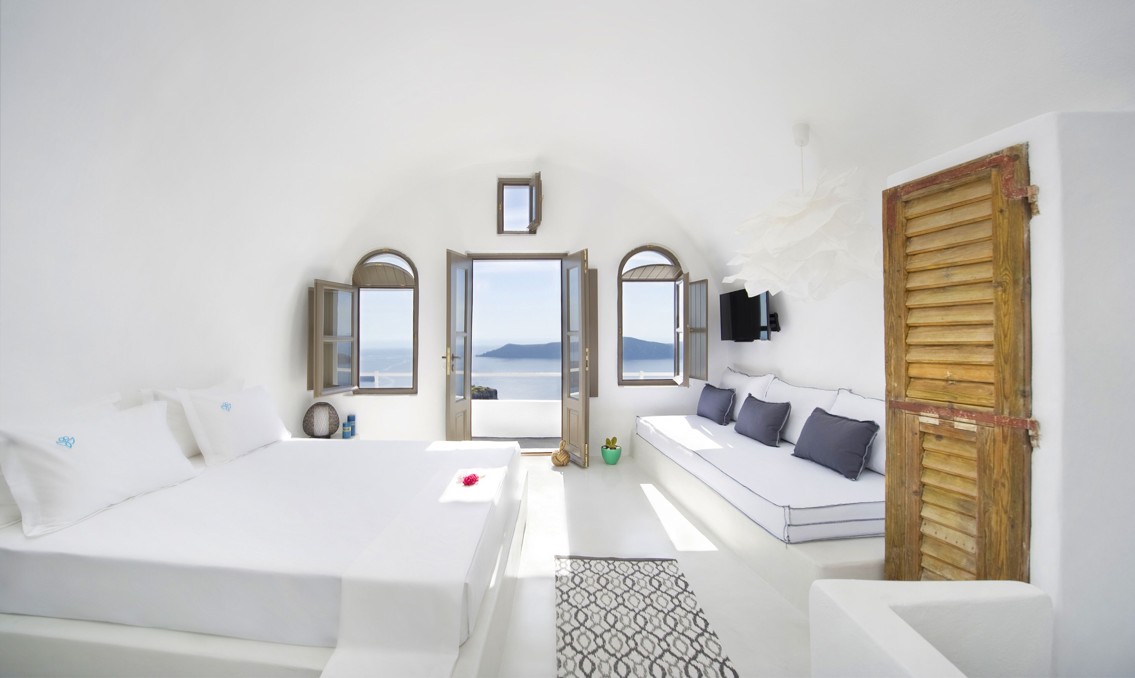 A bedroom with a large bed, a sofa, and a view of the sea.