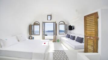 Un dormitorio con una cama grande, un sofá y vista al mar.