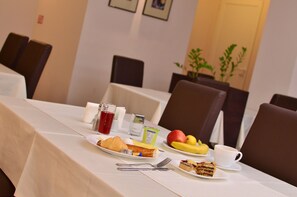 Et morgenbord med croissanter, frugt, en kop kaffe og en lille kage.