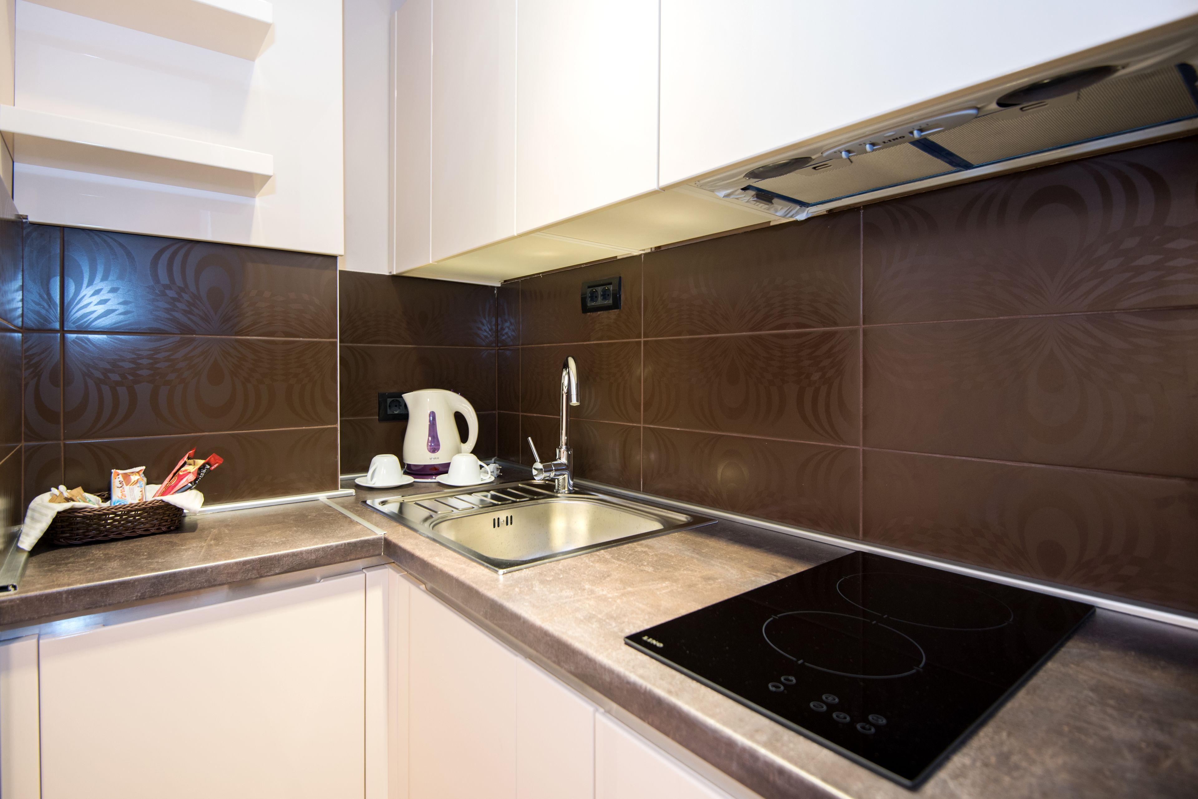 Una cucina moderna con piano cottura integrato, bollitore e lavandino.