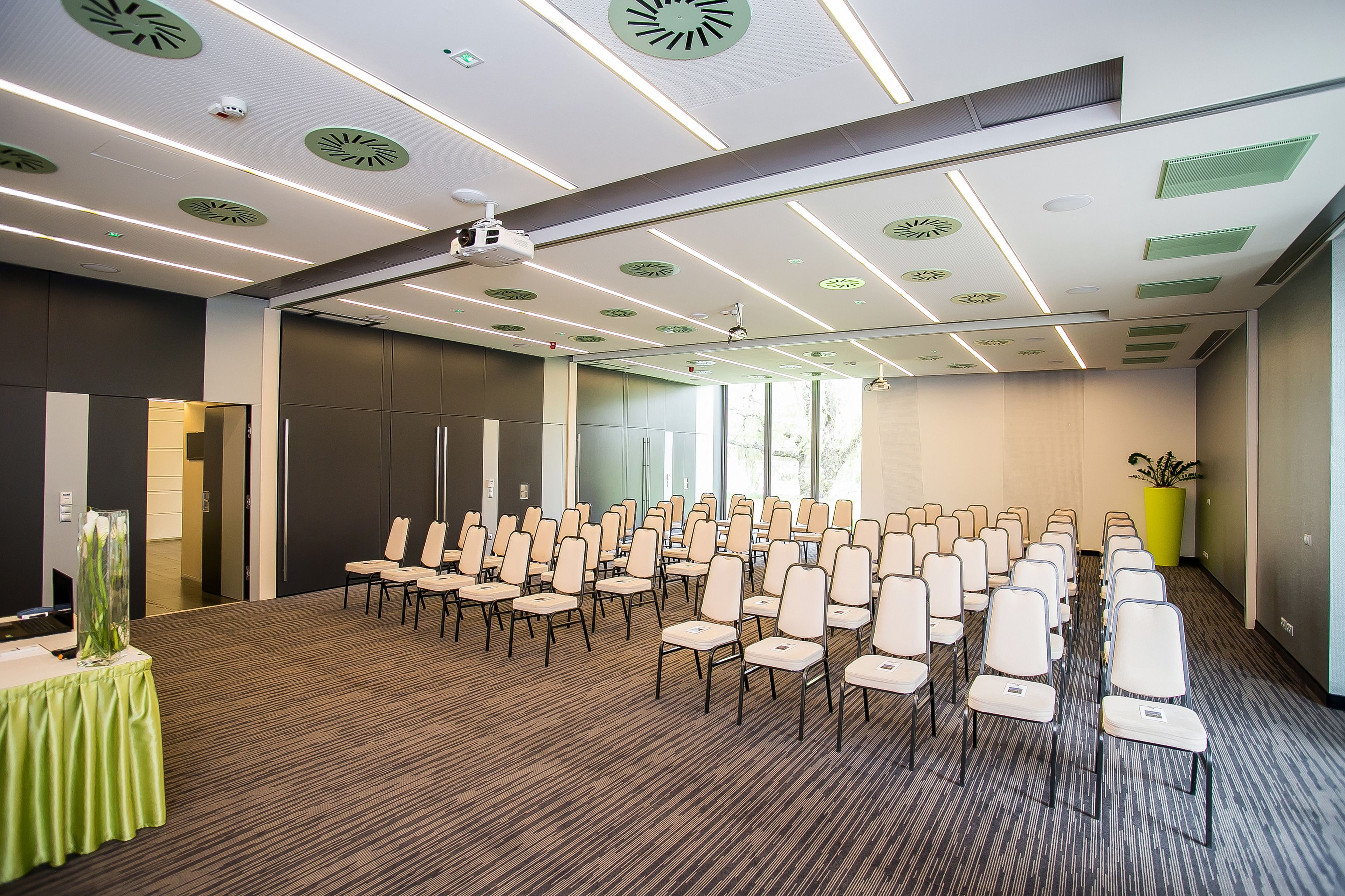 Una sala conferenze con file di sedie, un proiettore e un'ampia finestra.