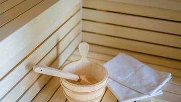 Una sauna de madera con una toalla blanca y un cucharón de madera.