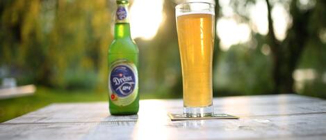 A bottle of beer and a glass on a wooden table outdoors.