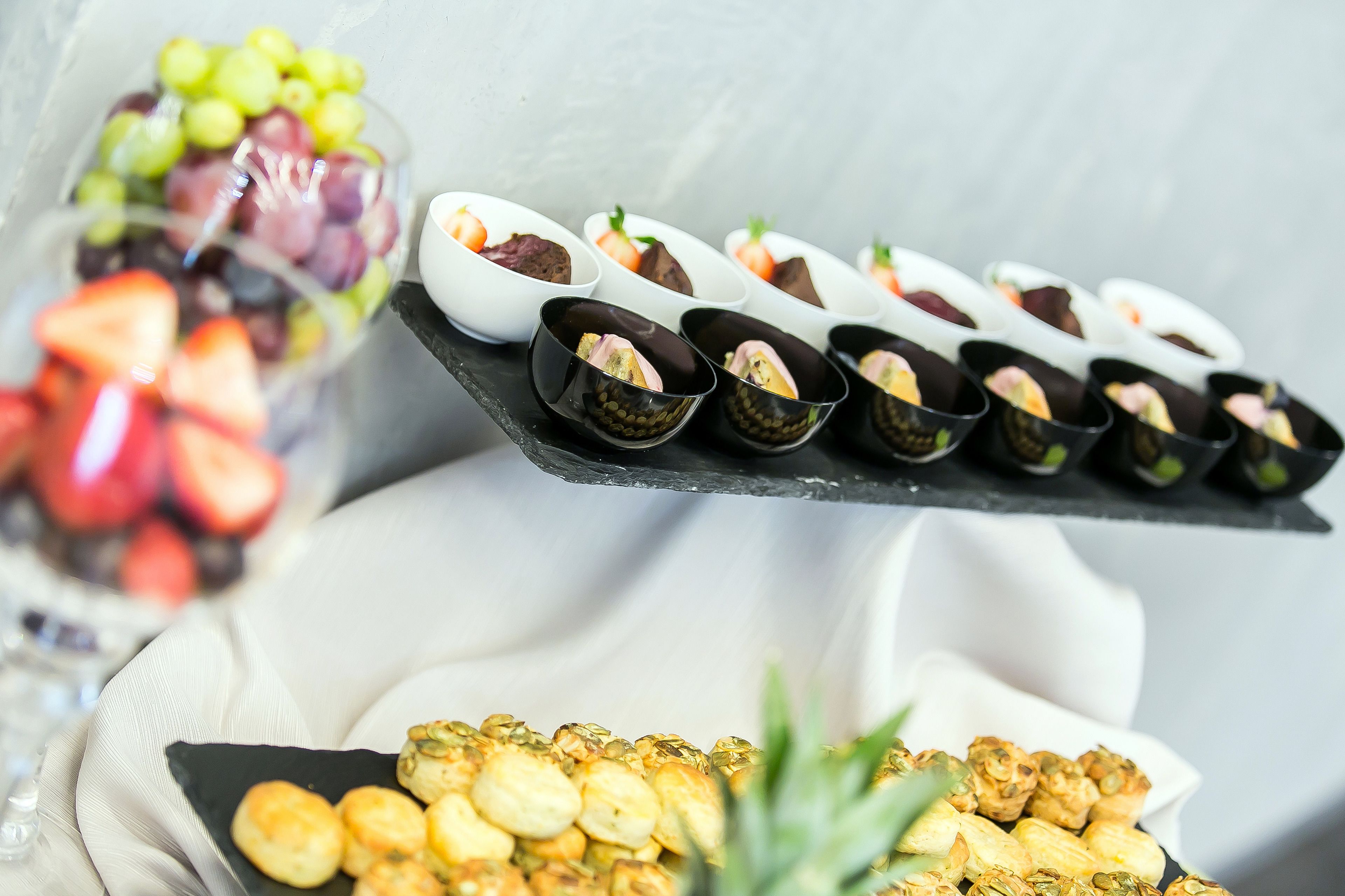 A variety of food items including a bowl of mixed fruits, a tray of small pastries, and a plate of fried snacks.