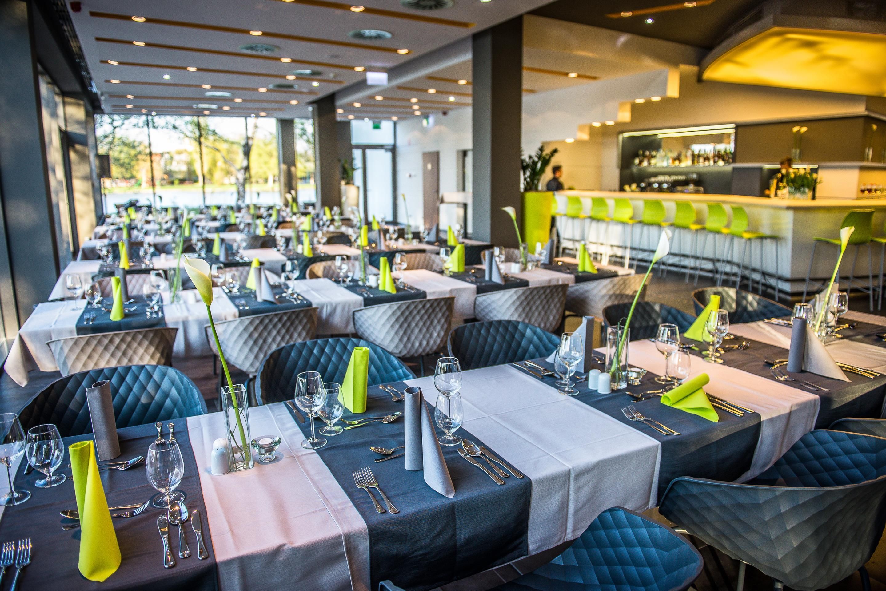 Un restaurante con varias mesas dispuestas para comer, con una zona de bar al fondo.