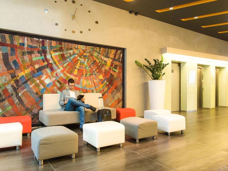 A hotel lobby with a large abstract painting, seating area, and a potted plant.