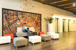 A hotel lobby with a large abstract painting, seating area, and a potted plant. - Best Western Plus Lakeside Hotel (Szekesfehervar)