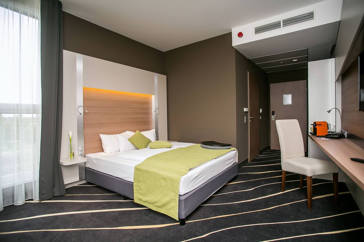 A hotel room with a bed, a desk, a chair, and a bathroom.