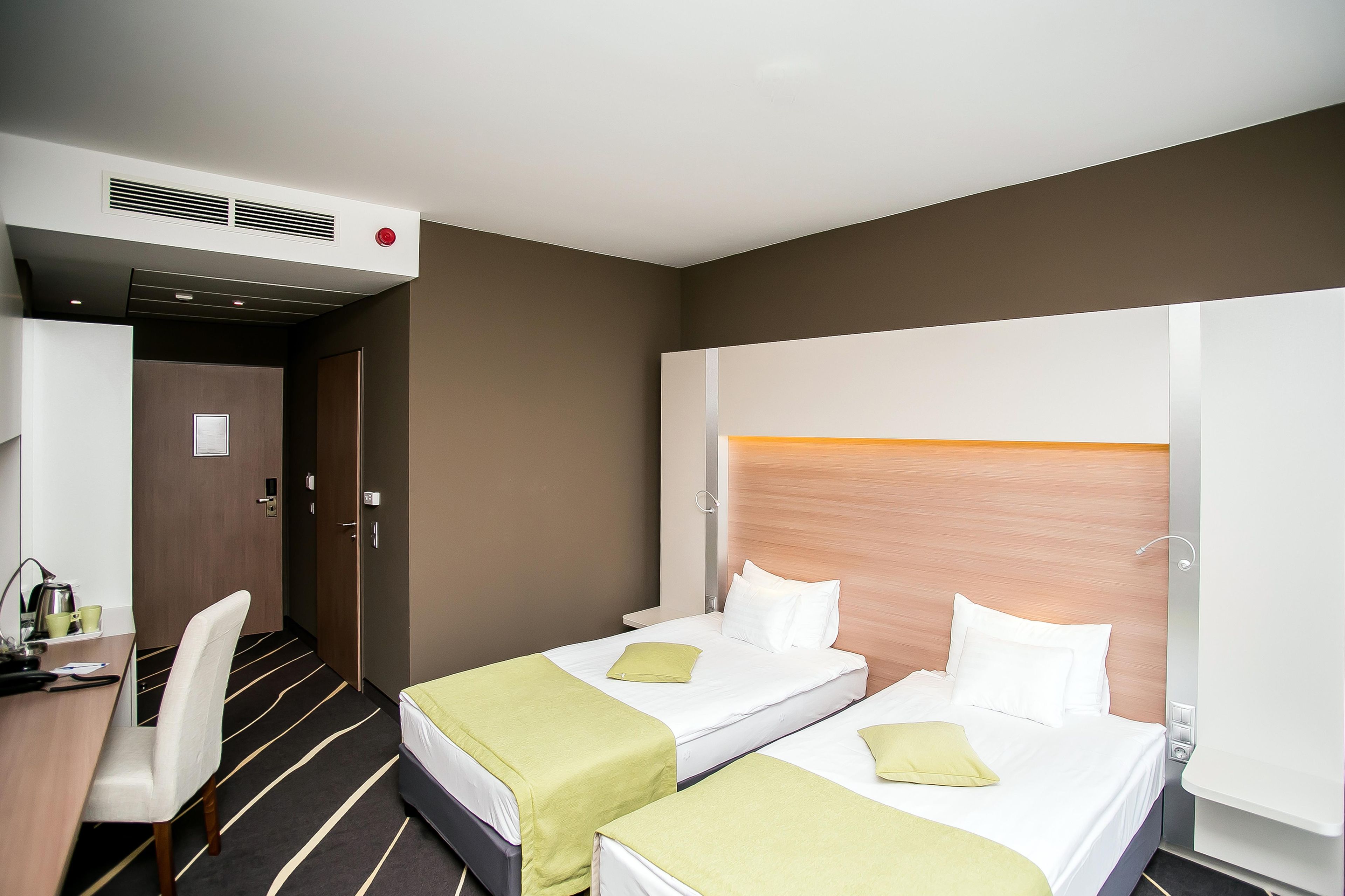 A hotel room with two beds, a desk, and a chair.