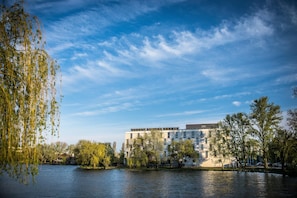 A riverside view with modern buildings, trees, and a clear sky. - Best Western Plus Lakeside Hotel (Szekesfehervar)
