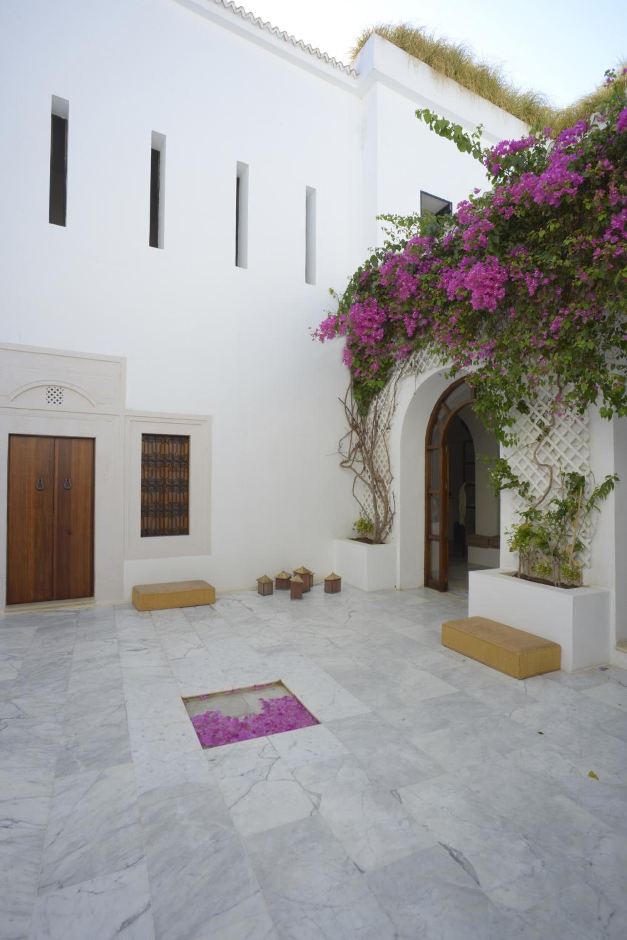Un cortile con pareti bianche, una porta in legno e una panchina.