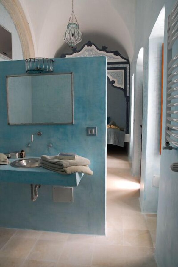 A bathroom with a blue accent wall, a sink, a mirror, and a hanging light fixture. - Dar Sabri (Nabeul)
