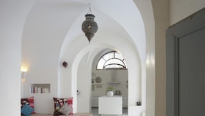 Un hall d’entrée spacieux aux murs blancs et aux arcades, qui mène à une cuisine.