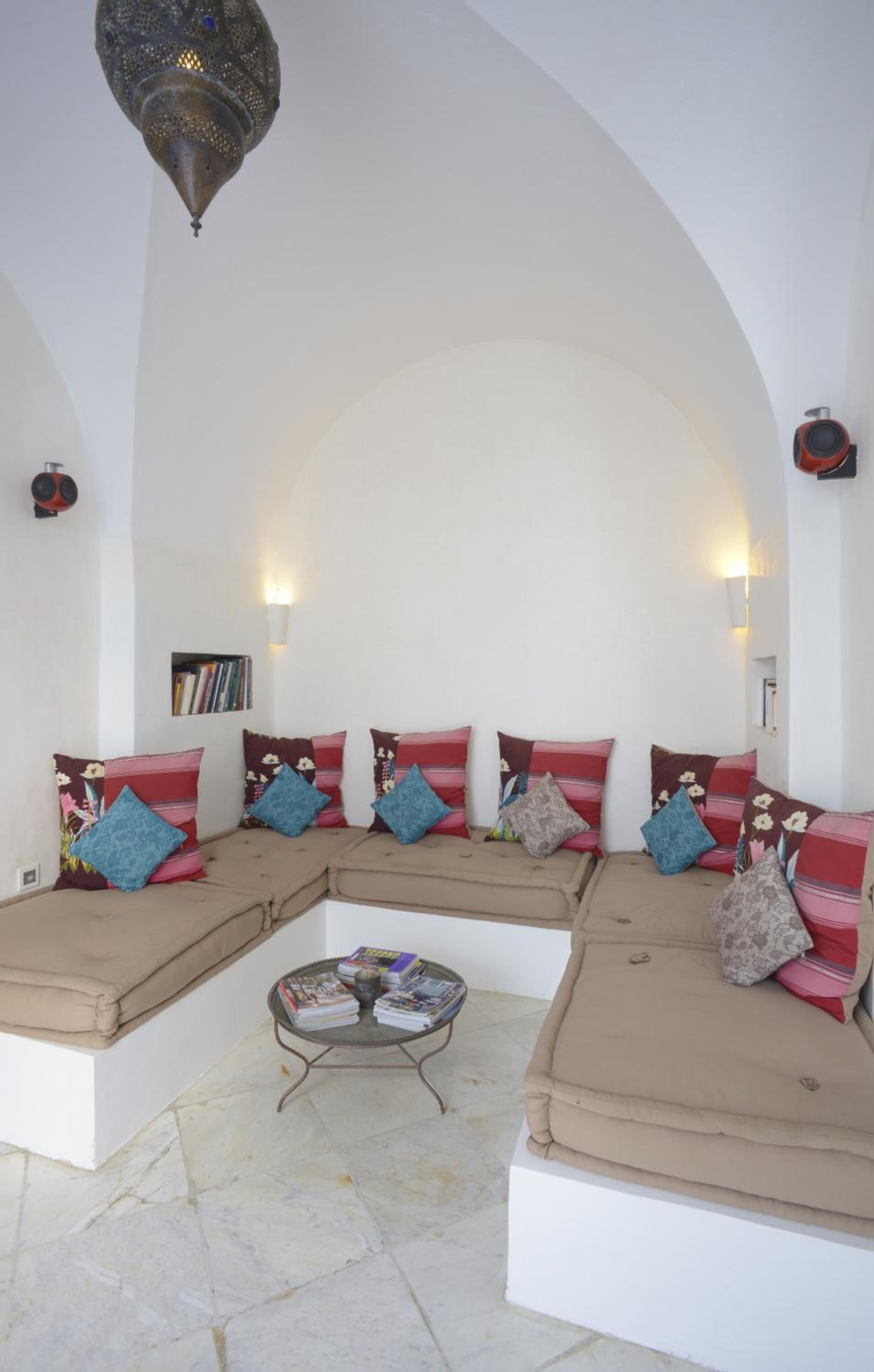 Una sala de estar acogedora con una pared blanca curva, un conjunto de sofás y una mesita baja con revistas.
