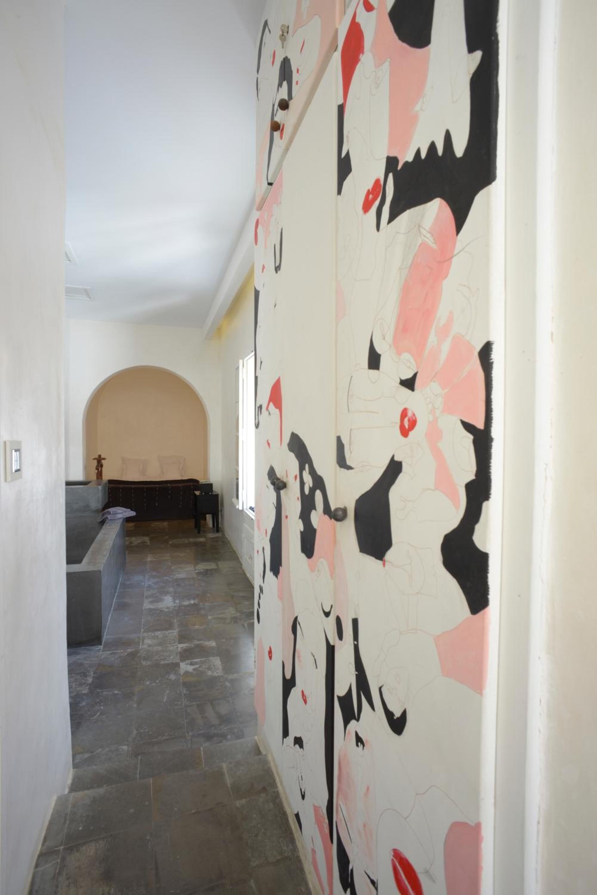 A hallway with a patterned wall, a bench, and a doorway leading to another room.