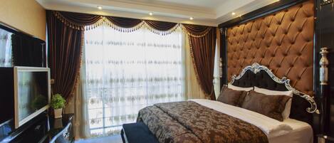 Un dormitorio con una cama grande, un televisor sobre una cómoda y una ventana con cortinas.