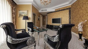 A luxurious room with ornate black and silver chairs, a glass coffee table, a flat-screen TV, and a chandelier. - Boutique Hotel Buta (Minsk)