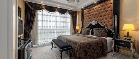 A luxurious bedroom with a large bed, a bench, a dresser, and a nightstand with lamps.
