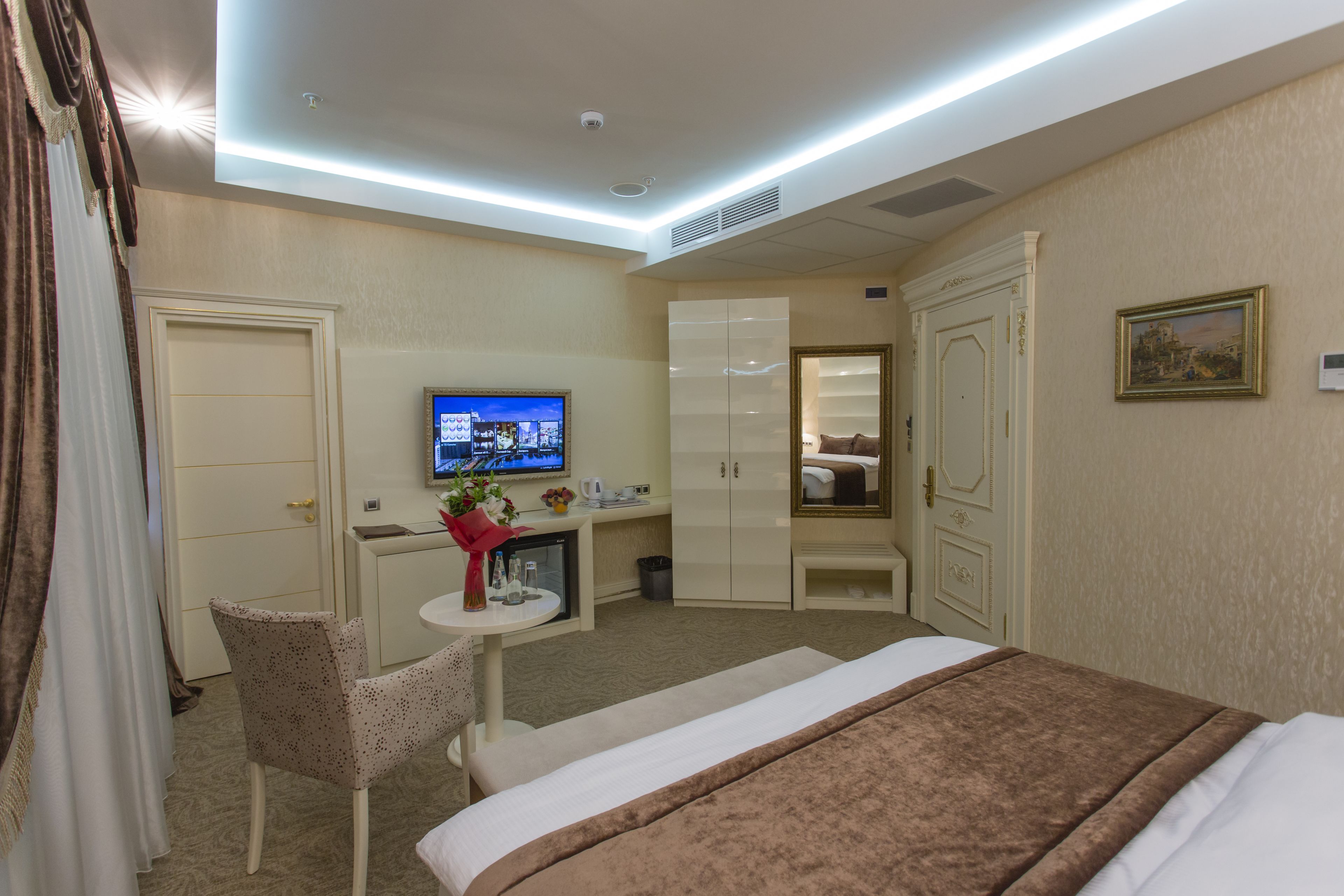 Una camera d'albergo con un letto, una scrivania, una sedia, una televisione e un armadio.