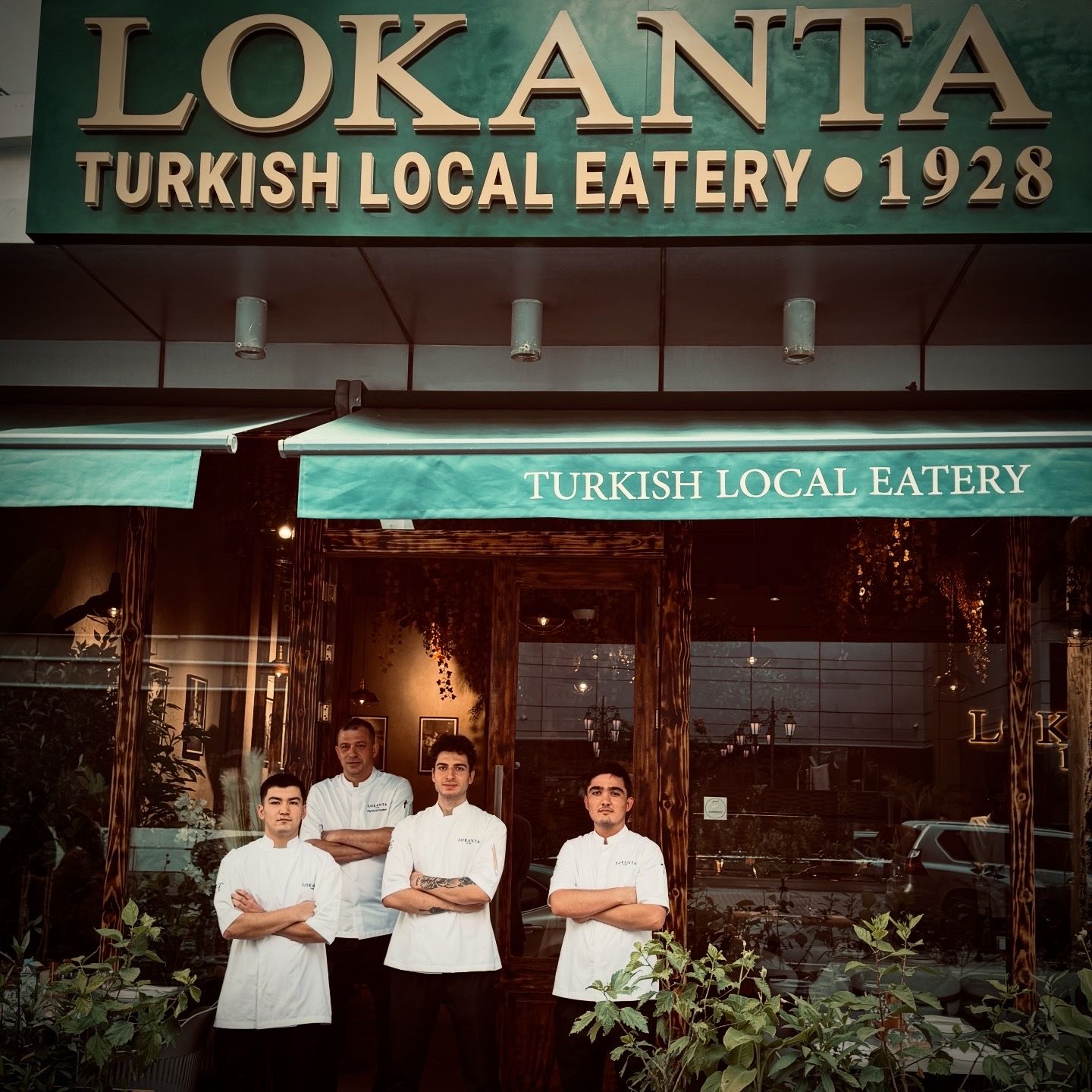 Exterior de Lokanta Turkish Local Eatery amb una tenda verda i una placa que mostra el nom i l'any d'obertura.