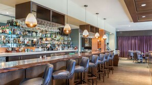 A bar area with multiple stools, a bar counter, and shelves stocked with bottles and glasses. - Best Western Premier Boulder Falls Inn (Lebanon)