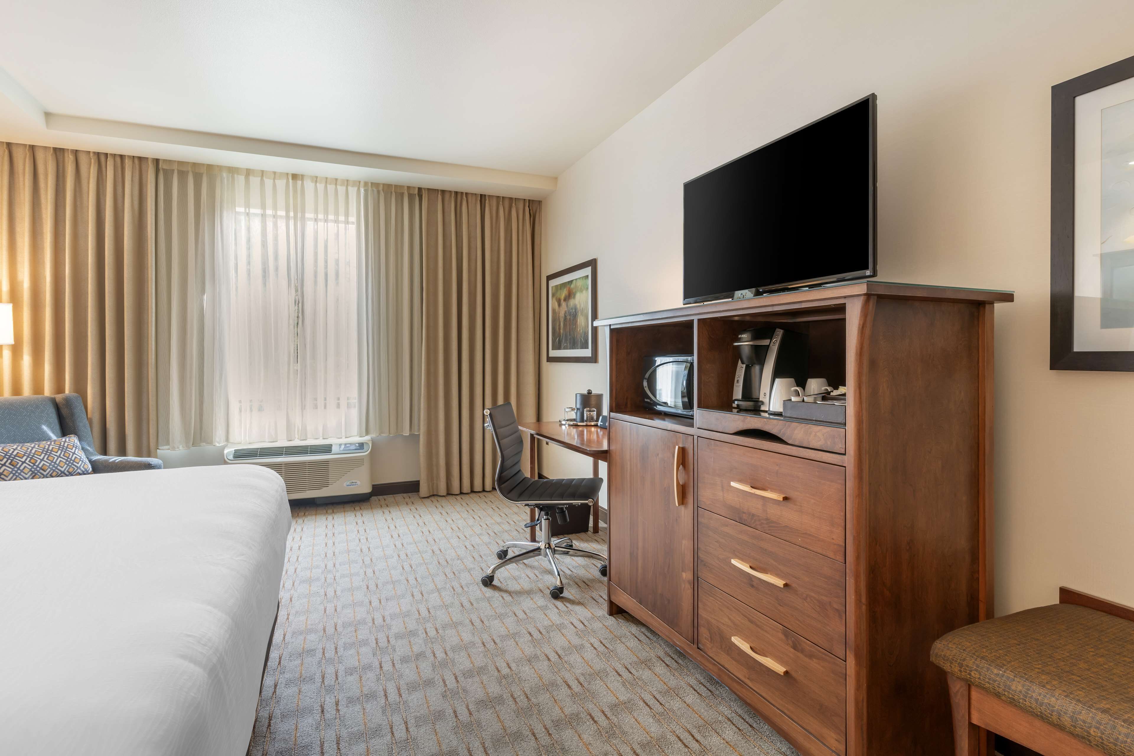Une chambre d’hôtel comprenant un lit, un bureau avec une chaise, une télévision et un placard.