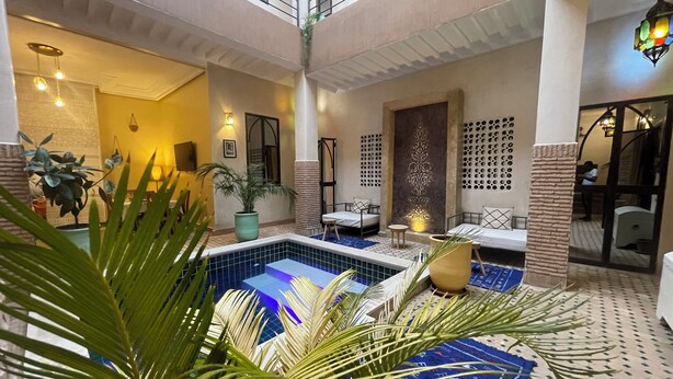 A hotel lobby with a central pool, seating areas, and decorative elements.