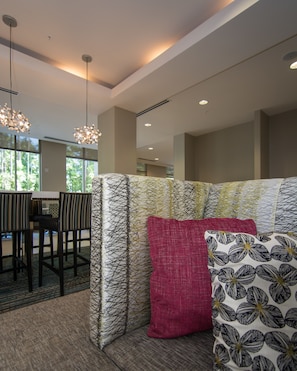 A modern living room with a sectional sofa, patterned cushions, and a dining area with chairs and a table. - Residence Inn Raleigh-Durham Airport/Brier Creek (Raleigh)