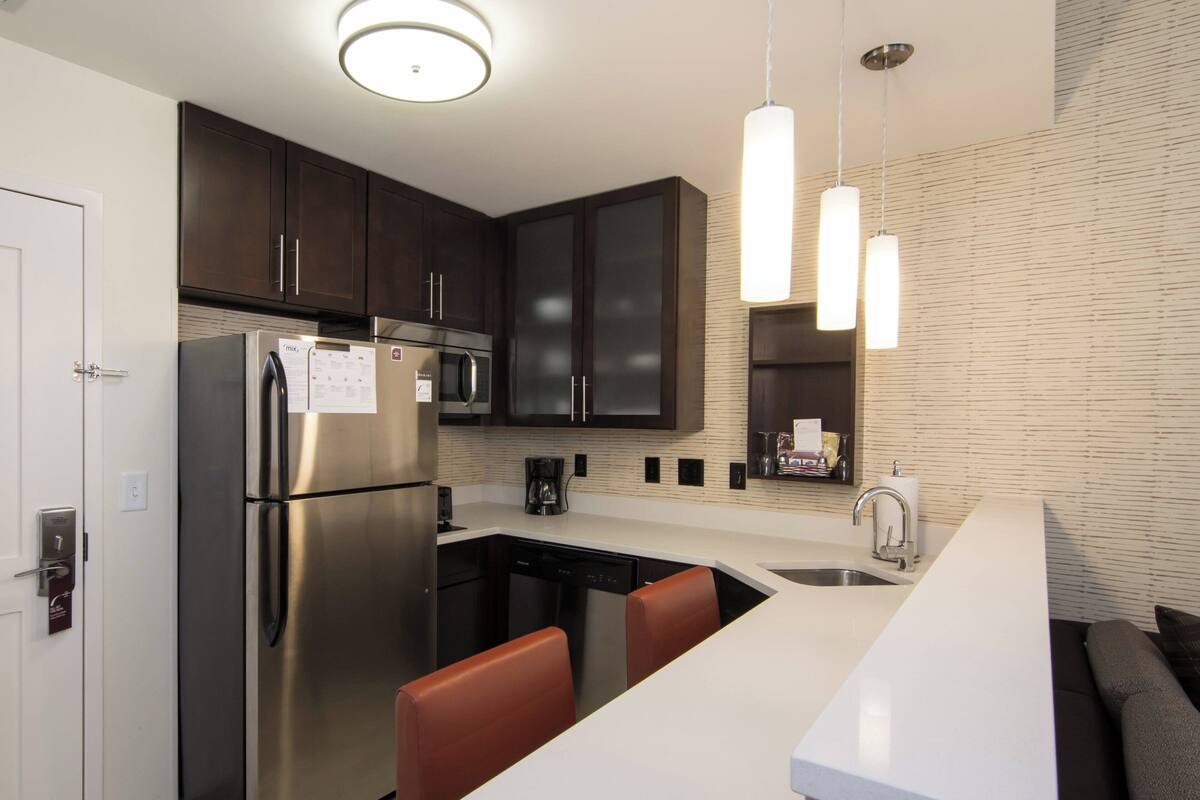 A modern kitchen with stainless steel appliances, a built-in dishwasher, and a white countertop.