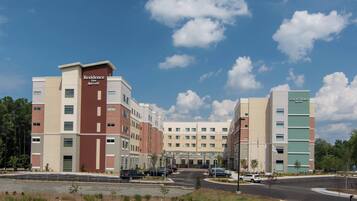 A multi-story hotel with a central entrance, parking area, and a courtyard.
