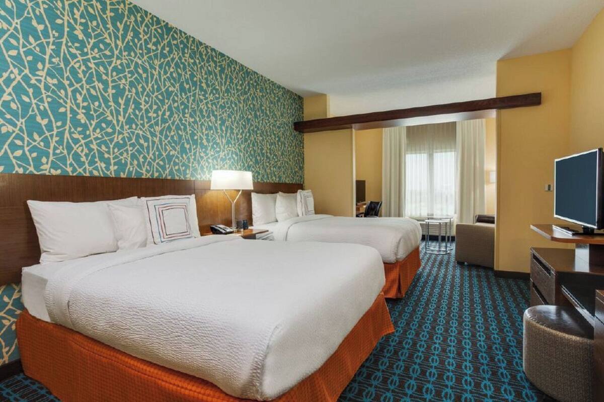 Une chambre d’hôtel avec deux lits, une télévision, un bureau et une chaise.