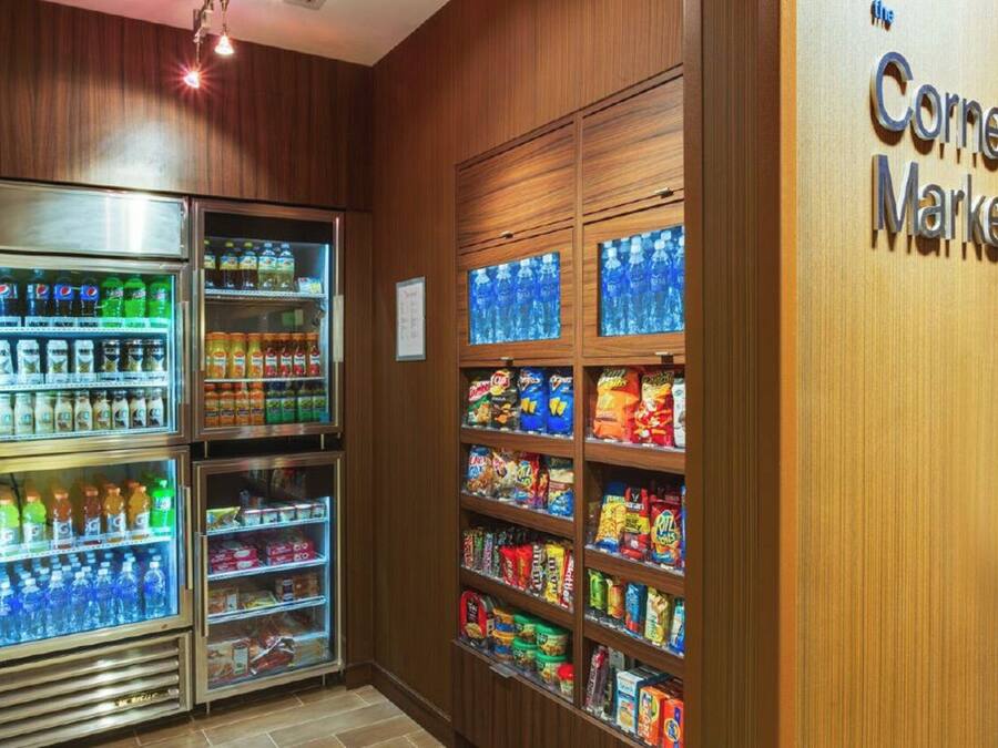 Un mercado de barrio con dispensadores de bebidas refrigeradas y estantes llenos de bocadillos y bebidas.