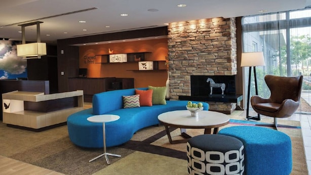 A modern lobby with a blue sofa, a stone fireplace, and a reception desk.
