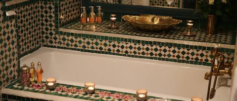 Un baño con piso de baldosas a cuadros, una bañera y velas.