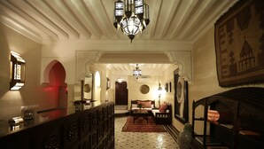 Un couloir avec un sol à motifs, un lustre, un canapé et une décoration murale.