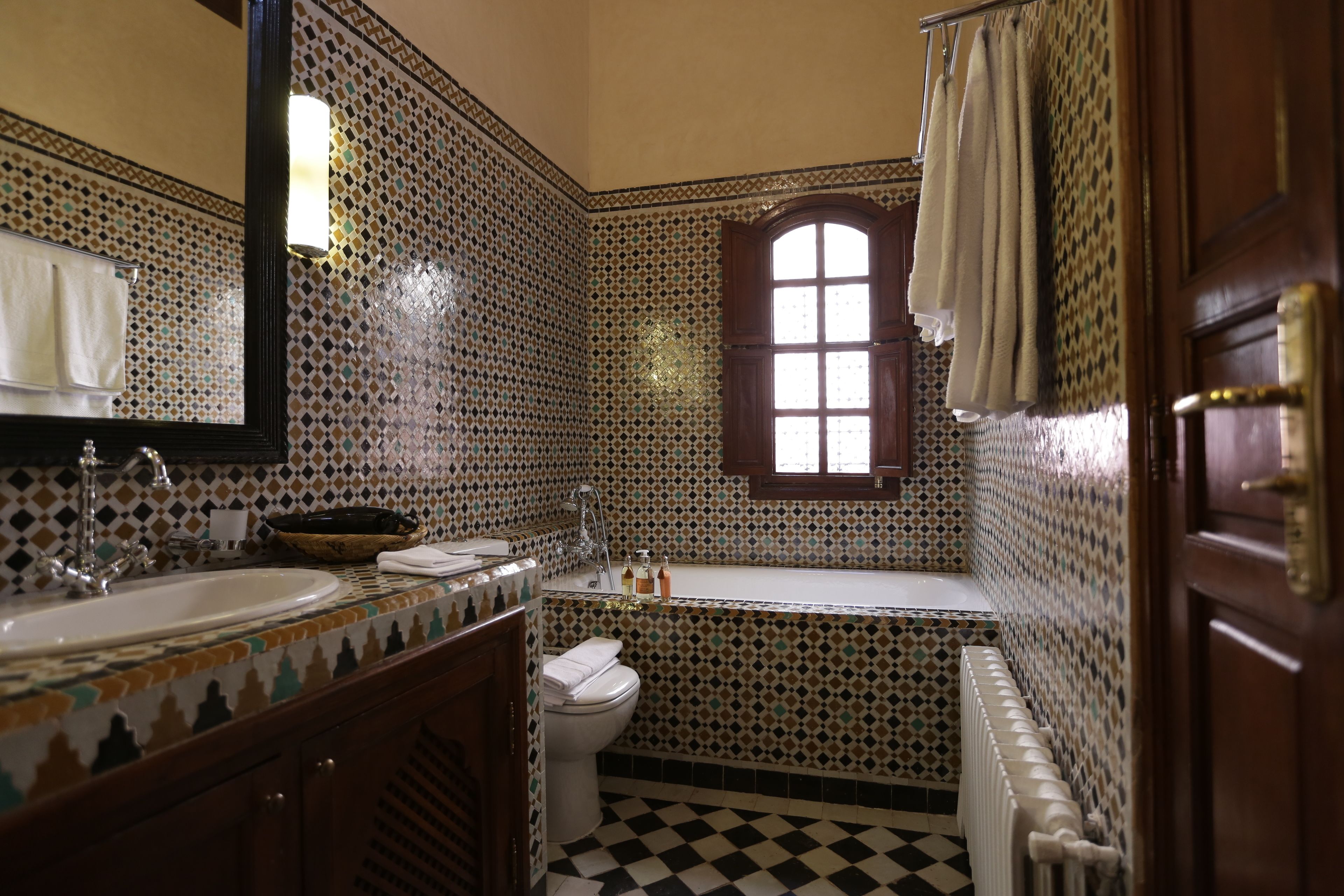 Un bagno con pavimento a scacchi, un lavandino, un WC e una vasca da bagno.