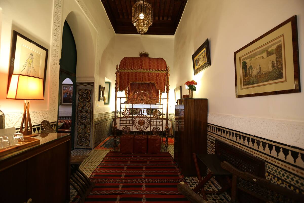 Una habitación tradicional con cama, candelabro y paredes con diseño.