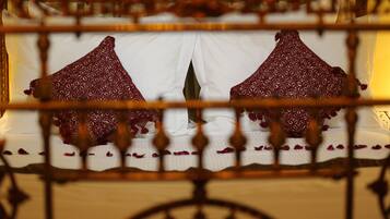 A bed with white linens and red patterned pillows, framed by a decorative wooden headboard.