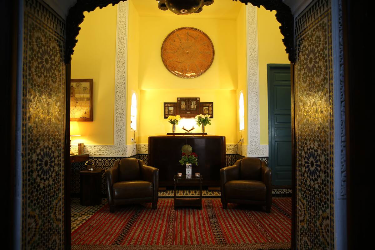 Una habitación con dos sillones de cuero, una mesita con un florero, un reloj de pared y un cuadro enmarcado.
