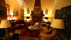 Un salon accueillant avec une cheminée, des fauteuils confortables et des lampes décoratives.
