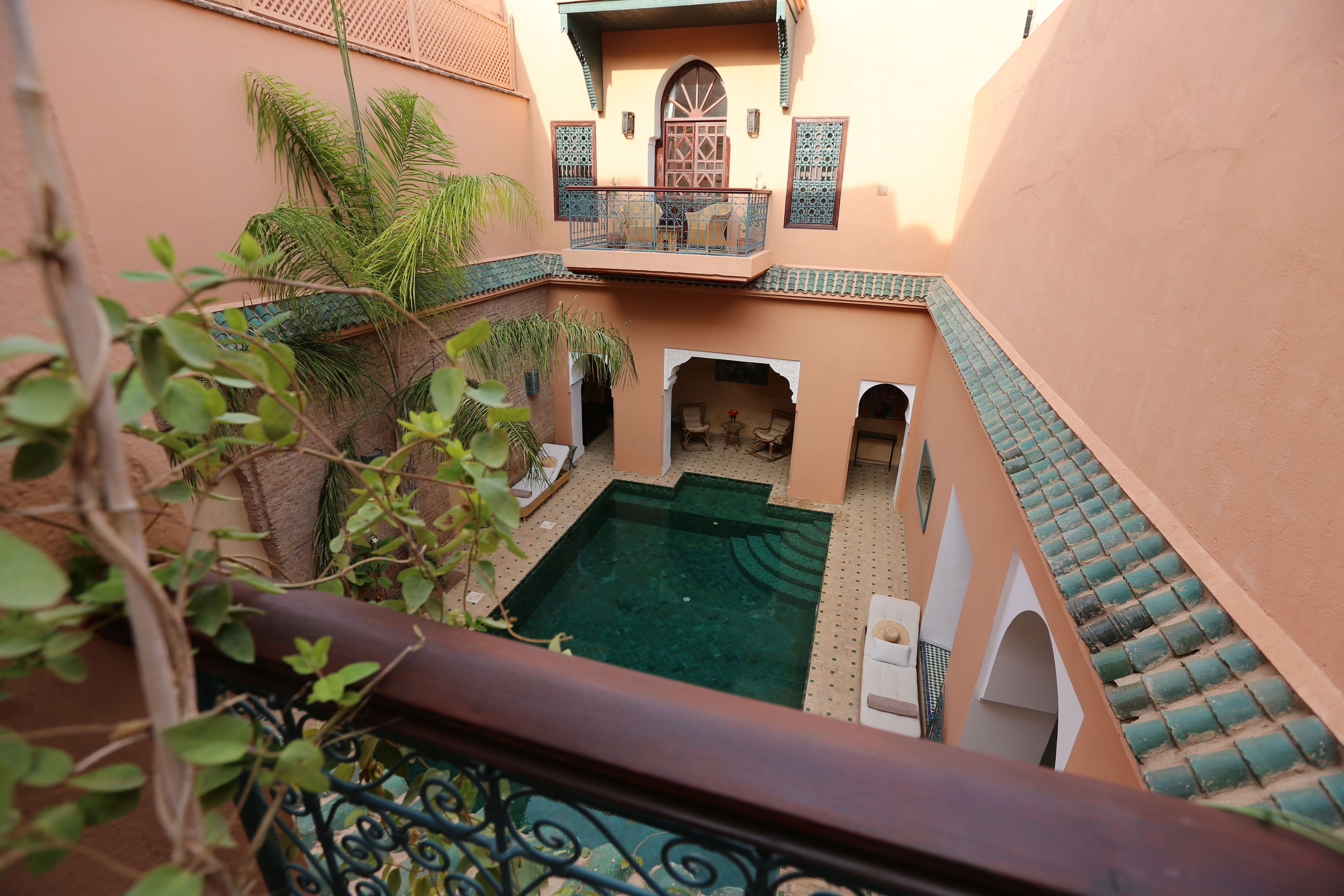 Un patio con piscina, un área de estar techada y un balcón con vista a la piscina.